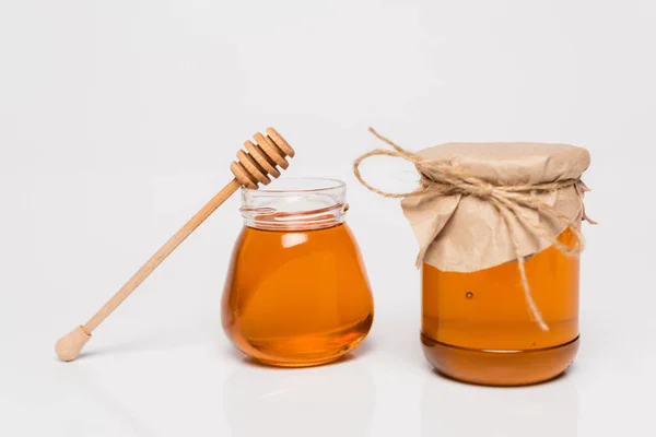 Wooden dipper near jars with yellow honey on white background — Stock Photo
