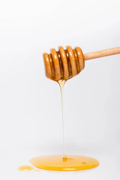 Fresh, liquid honey flowing from wooden dipper on white background — Stock Photo