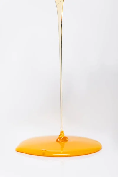 Fresh honey flowing on white background with copy space — Stock Photo