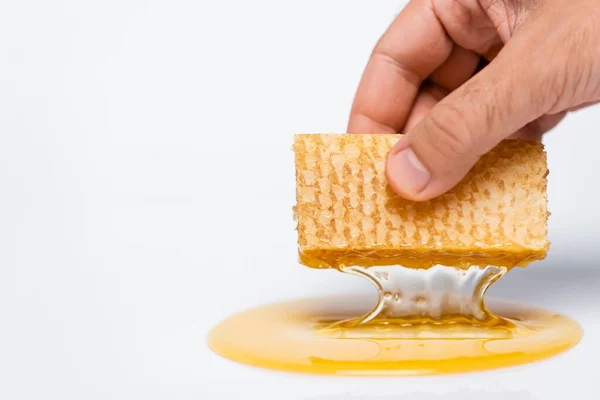 Vista cortada do homem segurando favo de mel com mel fresco e líquido no branco — Fotografia de Stock