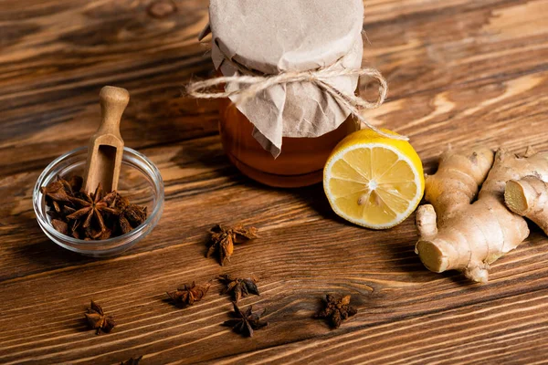 Fresh lemon and ginger root near honey jar and bowl with scoop and anise seeds — Stock Photo