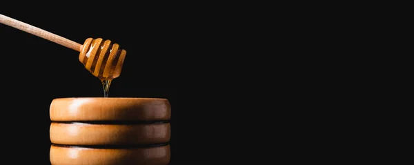 Невелика дерев'яна бочка біля занурювача з медом ізольована на чорному, банер — стокове фото