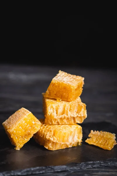 Vista de perto de favo de mel de corte na superfície escura isolada em preto — Fotografia de Stock