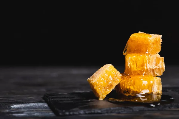 Pedaços de favo de mel com mel fresco em tábua de ardósia isolada em preto — Fotografia de Stock