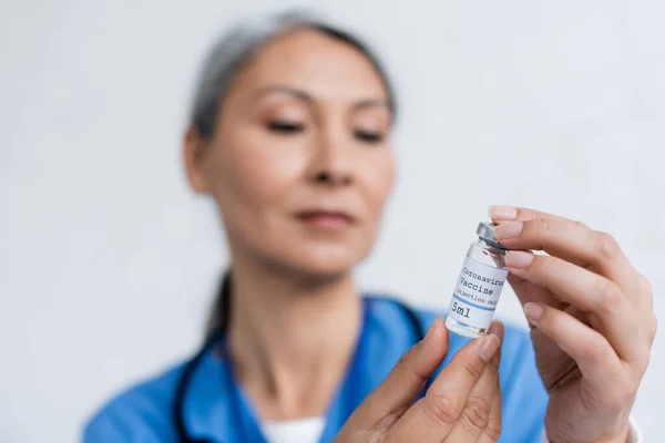 Blurred asian physician holding vial with coronavirus vaccine — Stock Photo