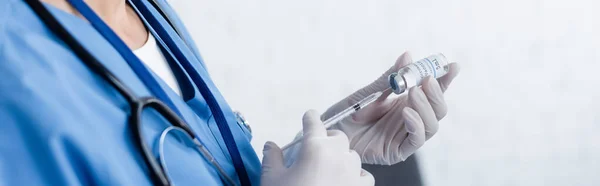 Vista parcial del médico en guantes de látex llenando la jeringa con la vacuna, banner - foto de stock