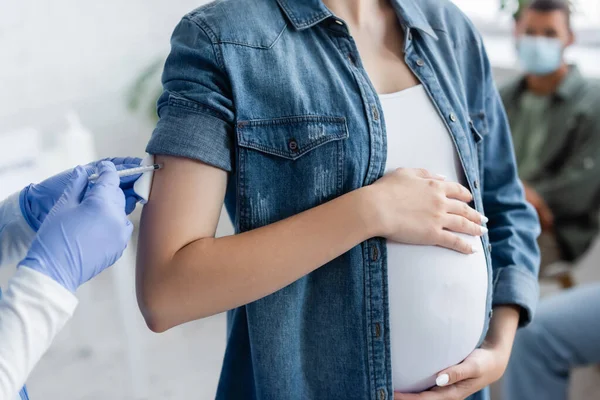 Vue recadrée du médecin dans des gants en latex administrant l'injection de vaccin à la femme enceinte à l'hôpital — Photo de stock