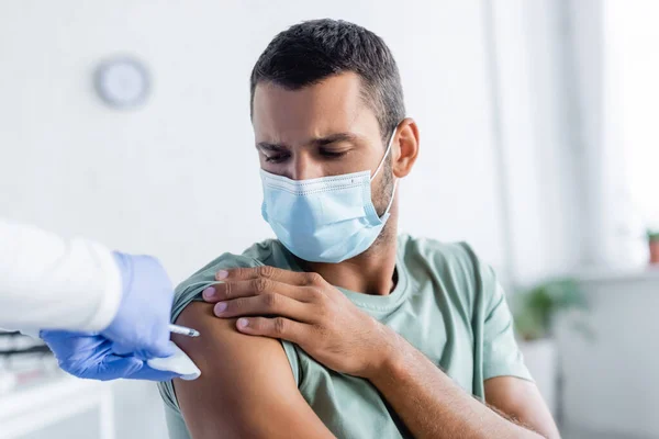 Enfermeira em luvas de látex vacinar o jovem em máscara médica — Fotografia de Stock