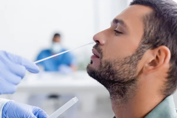 Doctor in latex gloves taking samples for coronavirus test from man in hospital — Stock Photo
