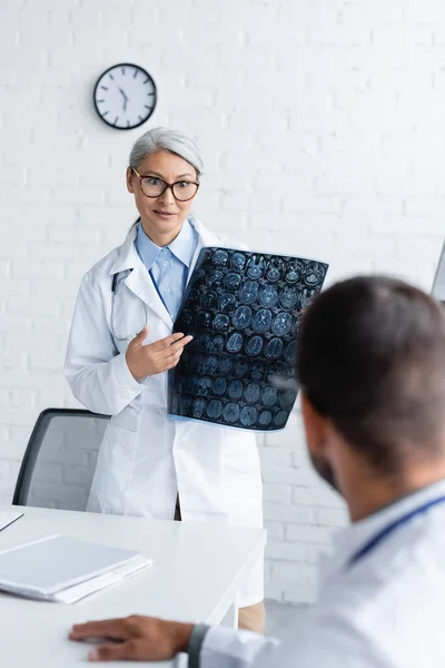 Sorprendido asiático médico mostrando cerebro mri scan a borrosa colega - foto de stock