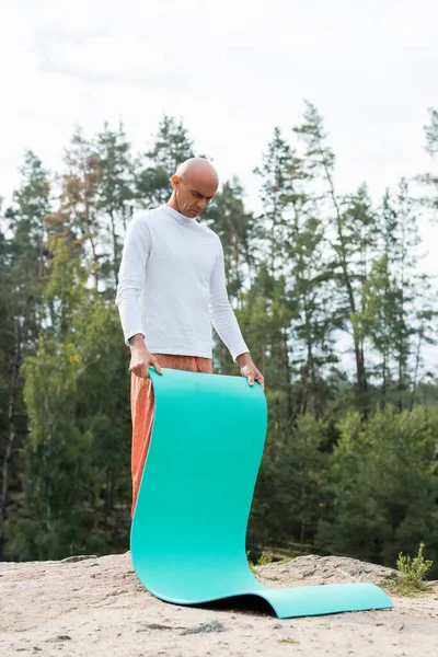Budista em camisola branca segurando tapete de ioga ao ar livre — Fotografia de Stock