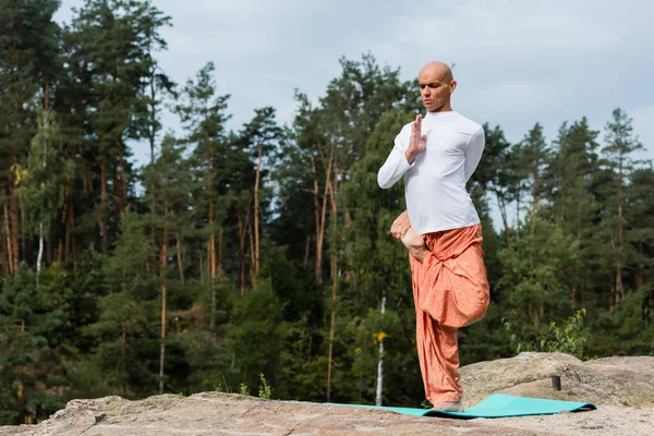 Full length view of buddhist practicing yoga in one legged tree pose outdoors — Stock Photo