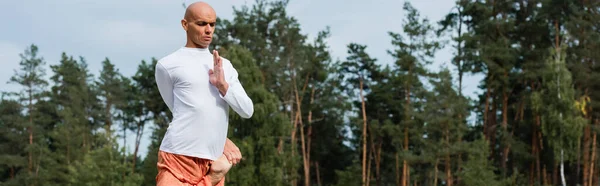 Bouddhiste en sweat-shirt blanc méditant dans une pose d'arbre à une jambe à l'extérieur, bannière — Photo de stock