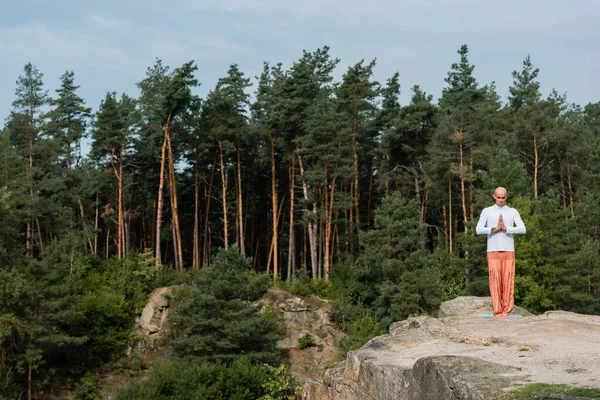 Vue complète du bouddhiste priant sur le rocher dans la forêt — Photo de stock