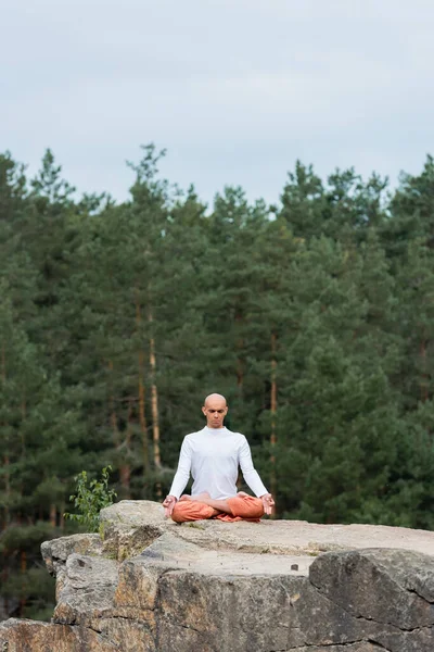 Buddhist meditating in lotus pose with closed eyes outdoors — Stock Photo