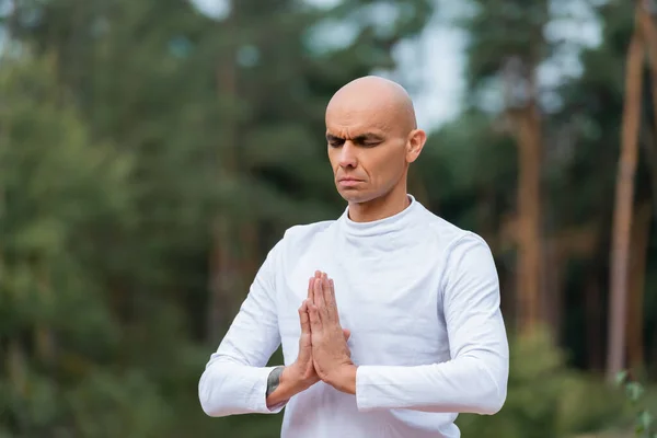 Buddhist in sweatshirt praying with closed eyes outdoors — Stock Photo