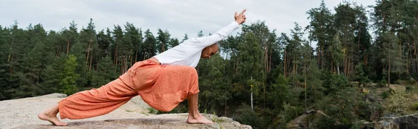 Vue latérale du bouddhiste en sweat-shirt blanc pratiquant la pose de fente en croissant, bannière — Photo de stock