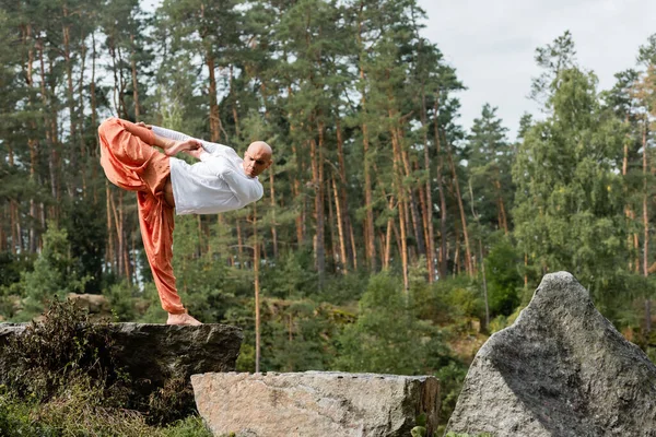 Budista descalzo practicando yoga en media luna posan sobre rocas en bosque - foto de stock