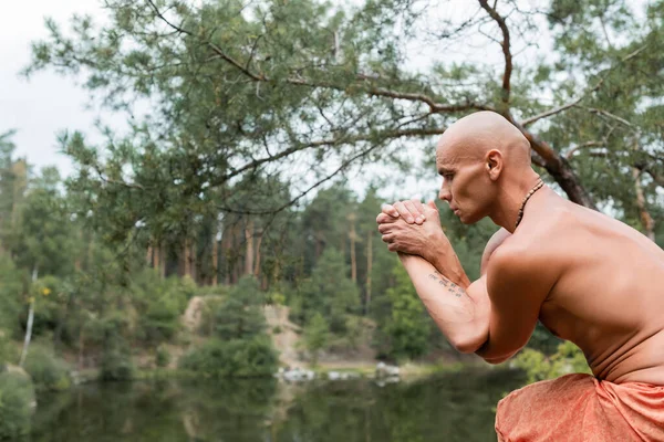 Shirtless buddhist practicing yoga pose in forest — Stock Photo