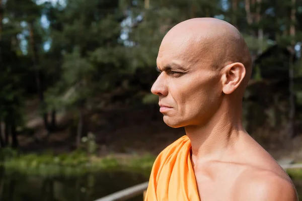 Portrait of buddhist in orange kasaya looking away outdoors — Stock Photo