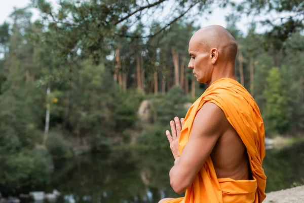 Visão lateral de budista com os olhos fechados meditando com as mãos orando na floresta — Fotografia de Stock