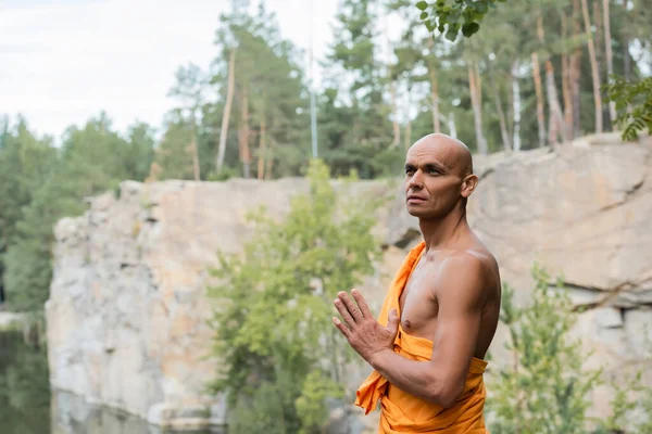 Budista olhando para longe enquanto meditava com as mãos orando ao ar livre — Fotografia de Stock