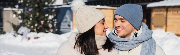 Feliz hombre y mujer en sombreros de punto mirándose el uno al otro, bandera - foto de stock