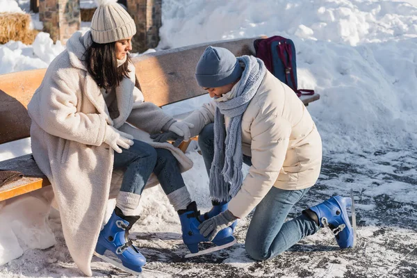 Jeune homme portant des patins à glace sur la femme en chapeau d'hiver — Photo de stock