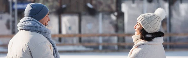 Happy young couple in winter hats looking at each other outside, banner — Stock Photo