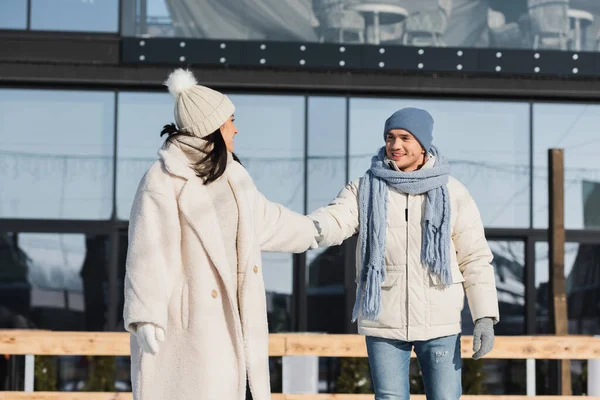 Jovem e positivo casal de mãos dadas enquanto patinava na pista de gelo — Fotografia de Stock