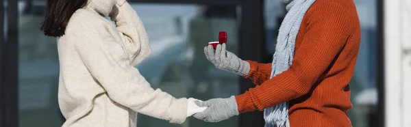 Cortado de homem segurando caixa com anel de casamento perto de mulher jovem no inverno, banner — Fotografia de Stock