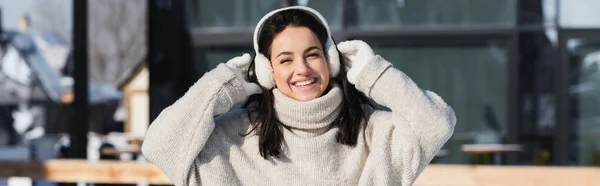 Alegre joven mujer en suéter y orejeras en invierno, pancarta - foto de stock