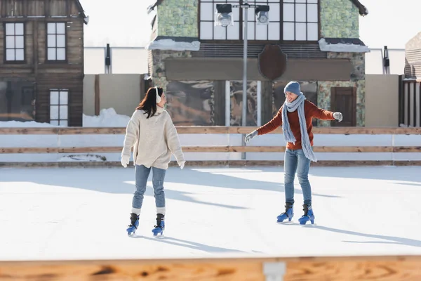 Comprimento total de casal alegre patinação na pista de gelo fora — Fotografia de Stock