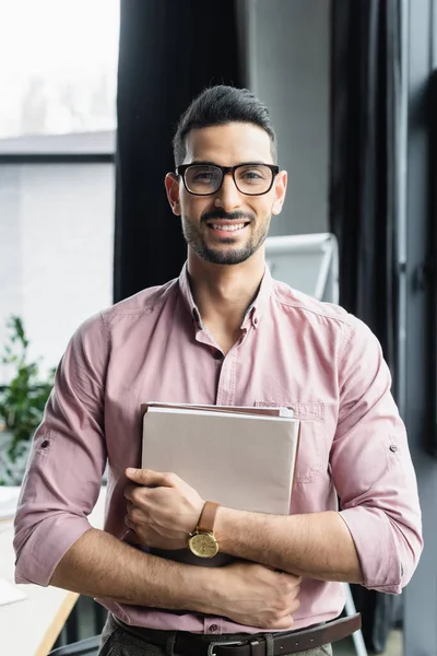 Счастливый арабский бизнесмен держит бумажные папки в офисе — стоковое фото