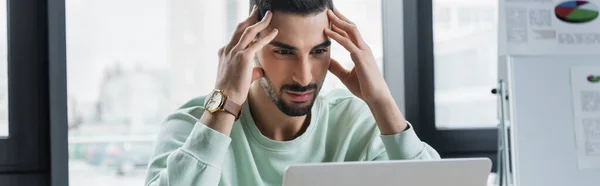 Focused arabian businessman in casual clothes looking at laptop in office, banner — Stock Photo