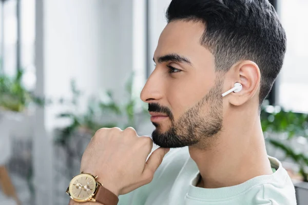 Seitenansicht eines muslimischen Geschäftsmannes mit drahtlosem Kopfhörer im Büro — Stockfoto