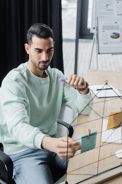 Young arabian businessman looking at blurred sticky notes in office — Stock Photo