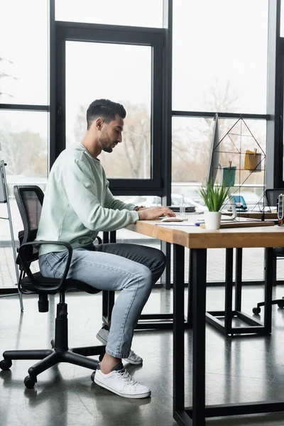 Side view of arabian businessman in casual clothes using computer while working in office — Stock Photo