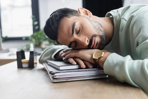 Hombre de negocios musulmán durmiendo en carpetas de papel y cuaderno en la oficina - foto de stock