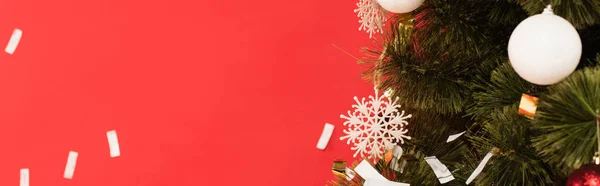 Vista de cerca del árbol de Navidad con copos de nieve decorativos y bolas aisladas en rojo, pancarta - foto de stock