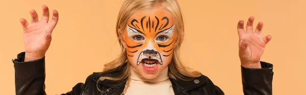 Menina com tigre rosto pintura rosnando e mostrando gesto assustador isolado no bege, banner — Fotografia de Stock