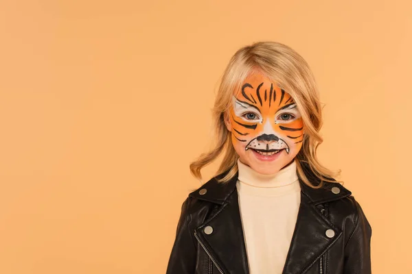 Niño feliz en el maquillaje del tigre sonriendo a la cámara aislada en beige - foto de stock