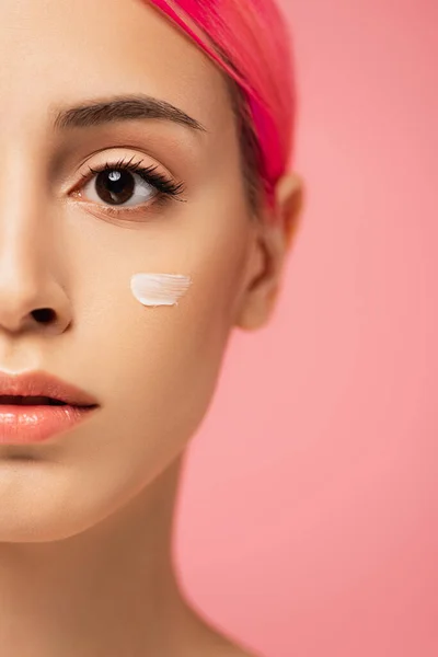 Abgeschnittene Ansicht einer jungen Frau mit gefärbten Haaren und Gesichtscreme auf der Wange isoliert auf rosa — Stockfoto