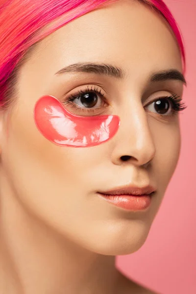 Vista de perto da jovem mulher com cabelo tingido e colágeno olho remendo isolado em rosa — Fotografia de Stock