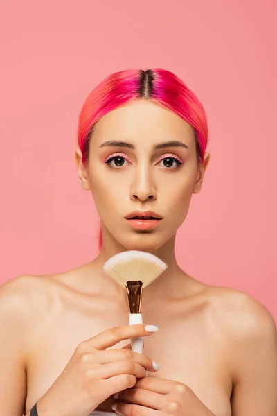 Jeune femme aux cheveux colorés tenant pinceau cosmétique isolé sur rose — Photo de stock