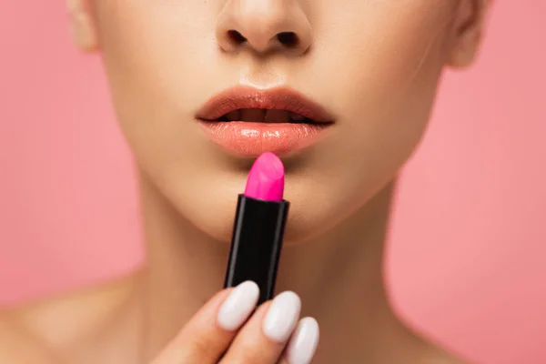 Vista recortada de mujer joven sosteniendo lápiz labial brillante aislado en rosa - foto de stock