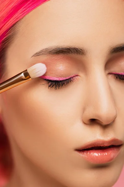 Close up of young woman with closed eyes applying eye shadow — Stock Photo