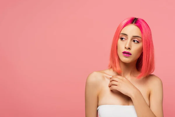 Jeune femme aux cheveux colorés et au maquillage lumineux regardant loin isolé sur rose — Photo de stock