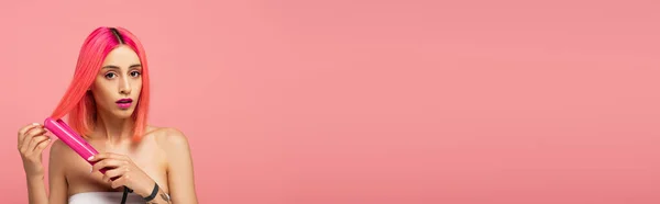 Giovane donna con capelli colorati utilizzando piastra per capelli isolata su rosa, banner — Foto stock