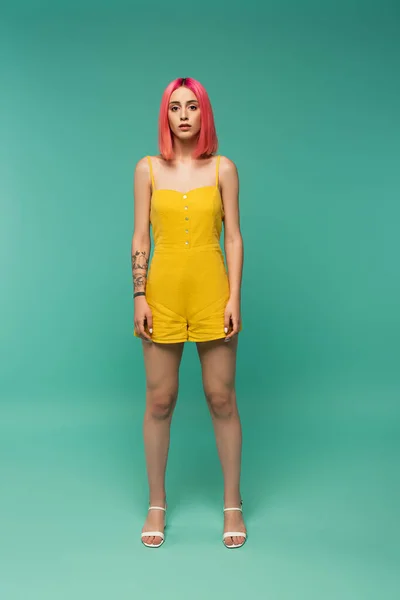 Full length of young woman with pink dyed hair posing on turquoise — Stock Photo